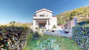 A modern two-story house with a balcony, a patio with outdoor furniture, and a well-maintained garden. - Villa in Kavac with beautiful sea view (Kavač)