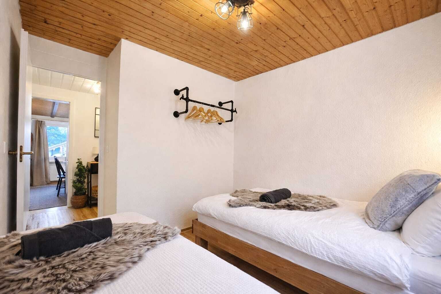 Une chambre avec deux lits, un plafond en bois et un luminaire fixé au mur.
