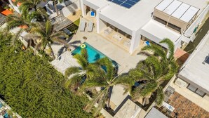 Ein Pool auf dem Dach mit Palmen, einer Lounge und einem Gebäude mit Solaranlagen.