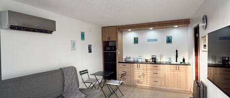 A compact living space with a kitchenette, a sofa, and a dining area.