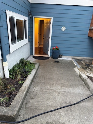 Uma casa com fachada azul, porta da frente, janela e um vaso de planta, além de um caminho de concreto.