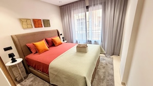 A hotel room with a large bed, a bedside table, a lamp, and a window with curtains. - Élégance Moderne à Gueliz 1 Bedroom and Living Room (Marrakech)