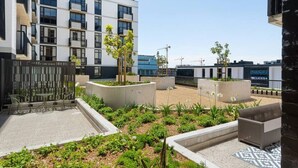 A courtyard with outdoor seating, planters, and a building with multiple floors and balconies. - Golden Nectar (Cape Town)