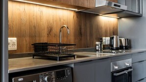 A modern kitchen with wooden cabinetry, a stainless steel range hood, a dishwasher, and a built-in oven. - Golden Nectar (Cape Town)