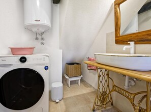 A compact bathroom with a washing machine, a sink with a wooden vanity, a mirror, and a white toilet. - Baladur Nature Apartments (Buzet)