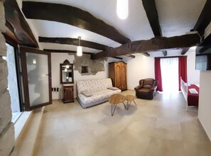 A room with a sofa, armchair, and a small table. There is a wardrobe, a mirror, and a window with curtains. - Baladur Nature Apartments (Buzet)
