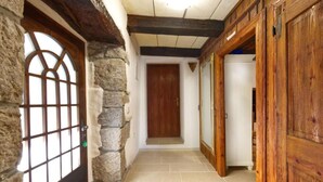 Un pasillo con paredes de piedra, puertas de madera y piso de baldosas.