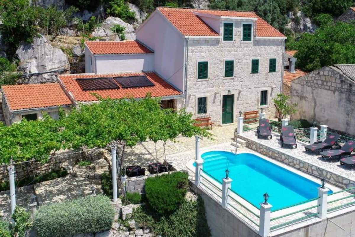 Un edificio in pietra con piscina e area salotto all'aperto.