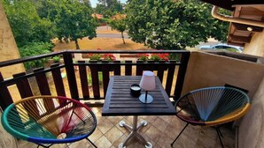 Ein Balkon mit Tisch, zwei Stühlen und einer Kerze.