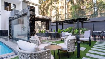 A poolside area with wicker furniture, a small table, and a pergola.