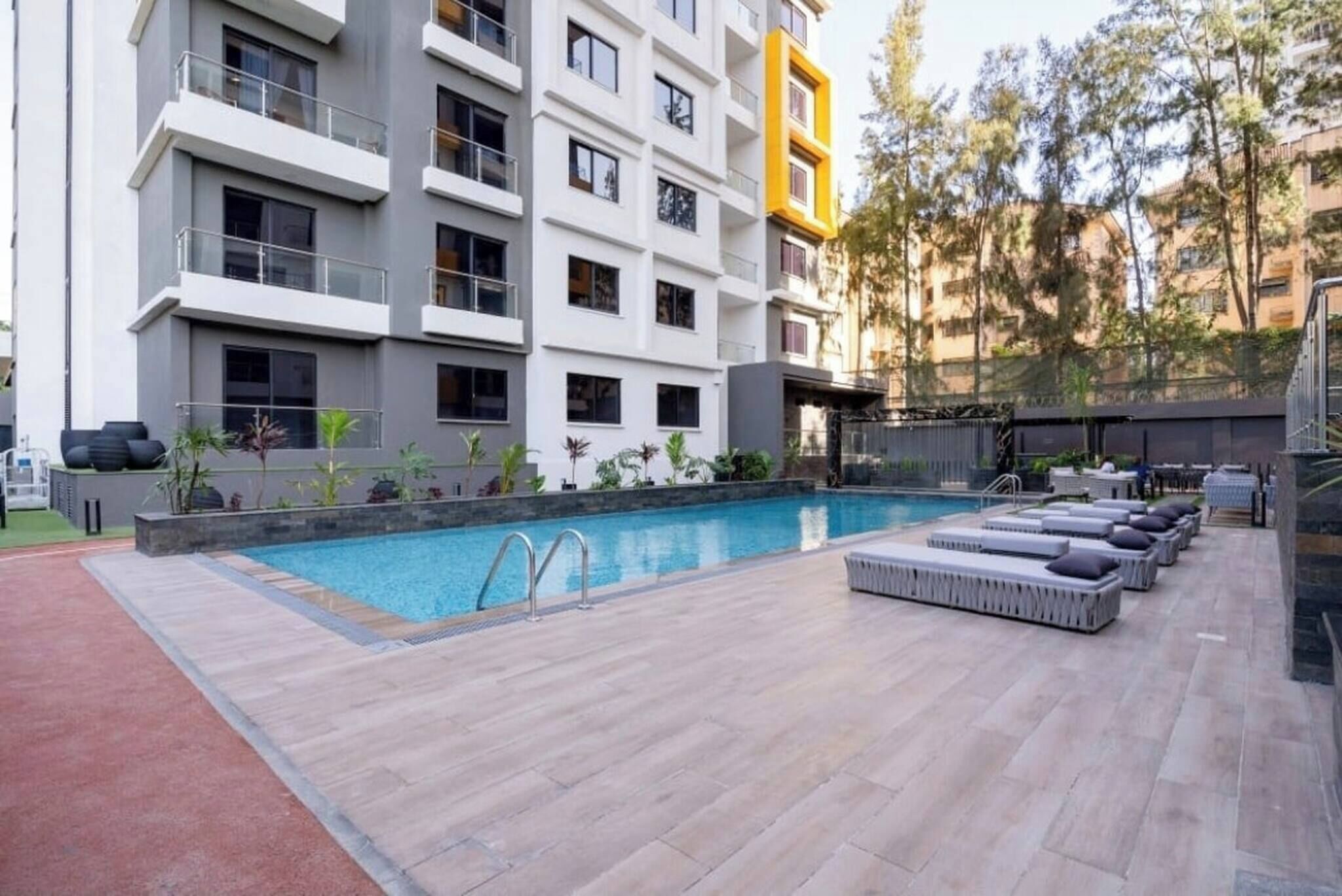 A modern building with a rooftop pool, outdoor seating, and a landscaped area.