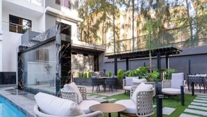 A modern outdoor patio with a pool, wicker furniture, and a pergola. - Executive one Bedroom Kilimani (Nairobi)