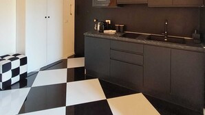 A modern kitchen with a black and white checkered floor, dark cabinetry, and a microwave. - The Rabbit Hole: Unique Design Stay in Milan Downtown with AC and Wifi (Milano)