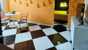 A room with a checkered floor, a wall with a pattern of spherical objects, a neon sign, and a small table with chairs. - The Rabbit Hole: Unique Design Stay in Milan Downtown with AC and Wifi (Milano)