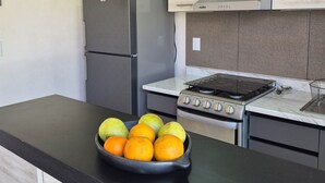 A modern kitchen with a black countertop, a stove, a refrigerator, and a bowl of fruit. - Family retreat: Relaxation and disconnection (Yautepec)
