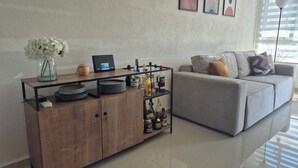 A modern living room with a grey sofa, a wooden cabinet with a glass top, and a wall-mounted shelf with various items. - Family retreat: Relaxation and disconnection (Yautepec)
