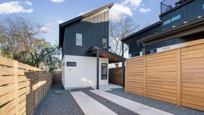 Ein modernes, zweistöckiges Haus mit Garage, Holzlattenzaun und einem Schotterweg.