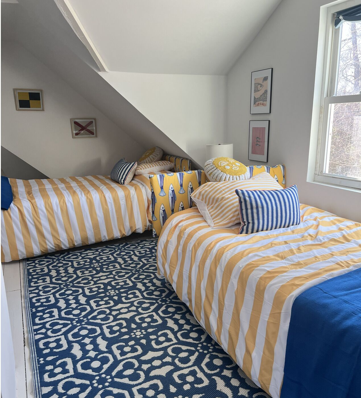 A bedroom with two beds, a patterned rug, and a window with a view.
