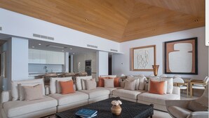 A modern living room with a sectional sofa, a coffee table, and a dining area. - Spectacular Kupuri Beach Oceanfront 6BR Luxury Villa, Infinity Pool, Chef (Punta Mita)