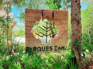 A sign with a woven design and a tree silhouette, reading "DR QUOTES ZAM". - Centric 2BD Condo in Aldea Zama (Tulum)