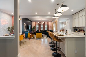 Una cocina moderna con una isla central, taburetes de bar y un comedor con sofá y sillas.
