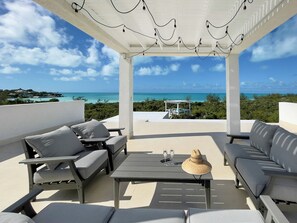 A covered outdoor seating area with a view of the ocean, a pool, and a gazebo. - StarFish Villa 3-Bed, 3.5- Bath in Turks & Caicos Islands with AC (Provindenciales)
