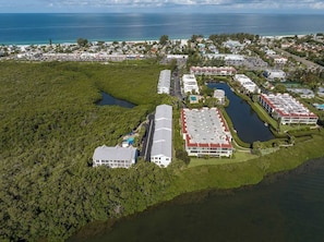 Eine Luftaufnahme eines Küstenresorts mit mehreren Gebäuden, einer Marina und einer großen Wasserfläche.
