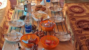 Ruokapöytä, jonka päällä on erilaisia ruoka-aineita ja ruokailuvälineitä, vesipullo ja vedenkeitin.