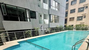 Ein Pool mit Metallgeländer, umgeben von einem Gebäude mit mehreren Stockwerken und großen Fenstern.