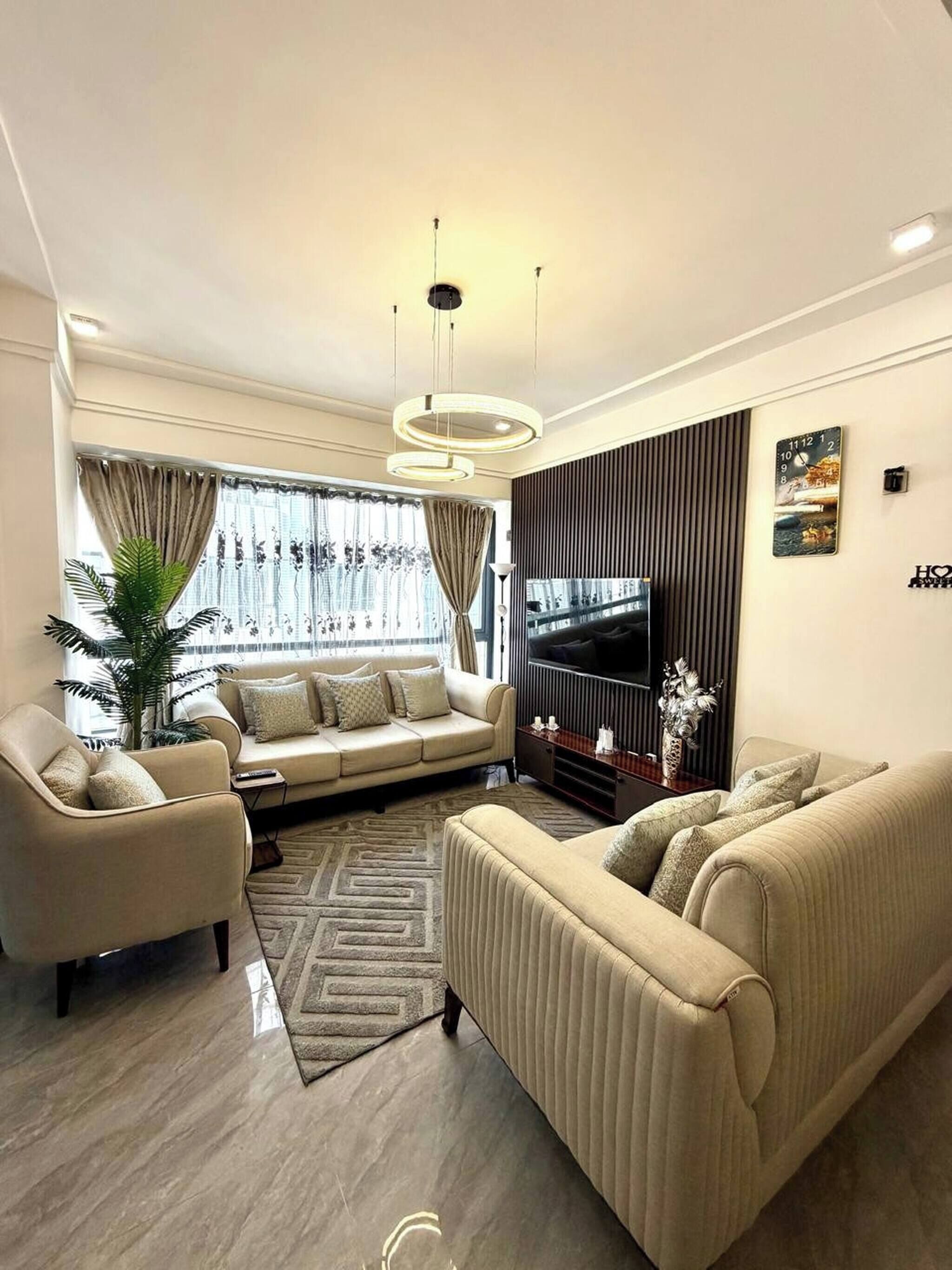Una sala moderna con un conjunto de sofás, un televisor y un panel decorativo en la pared.