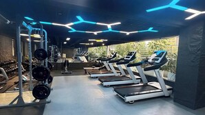 Ein Fitnessstudio mit Laufbändern, Gewichtstrainern und Blick auf Grünflächen.