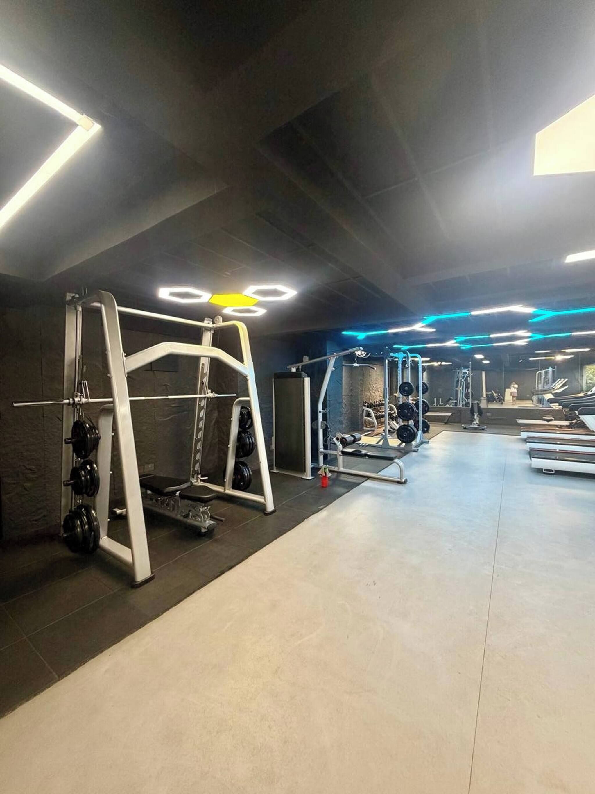 A gym with weightlifting equipment, treadmills, and a bench.