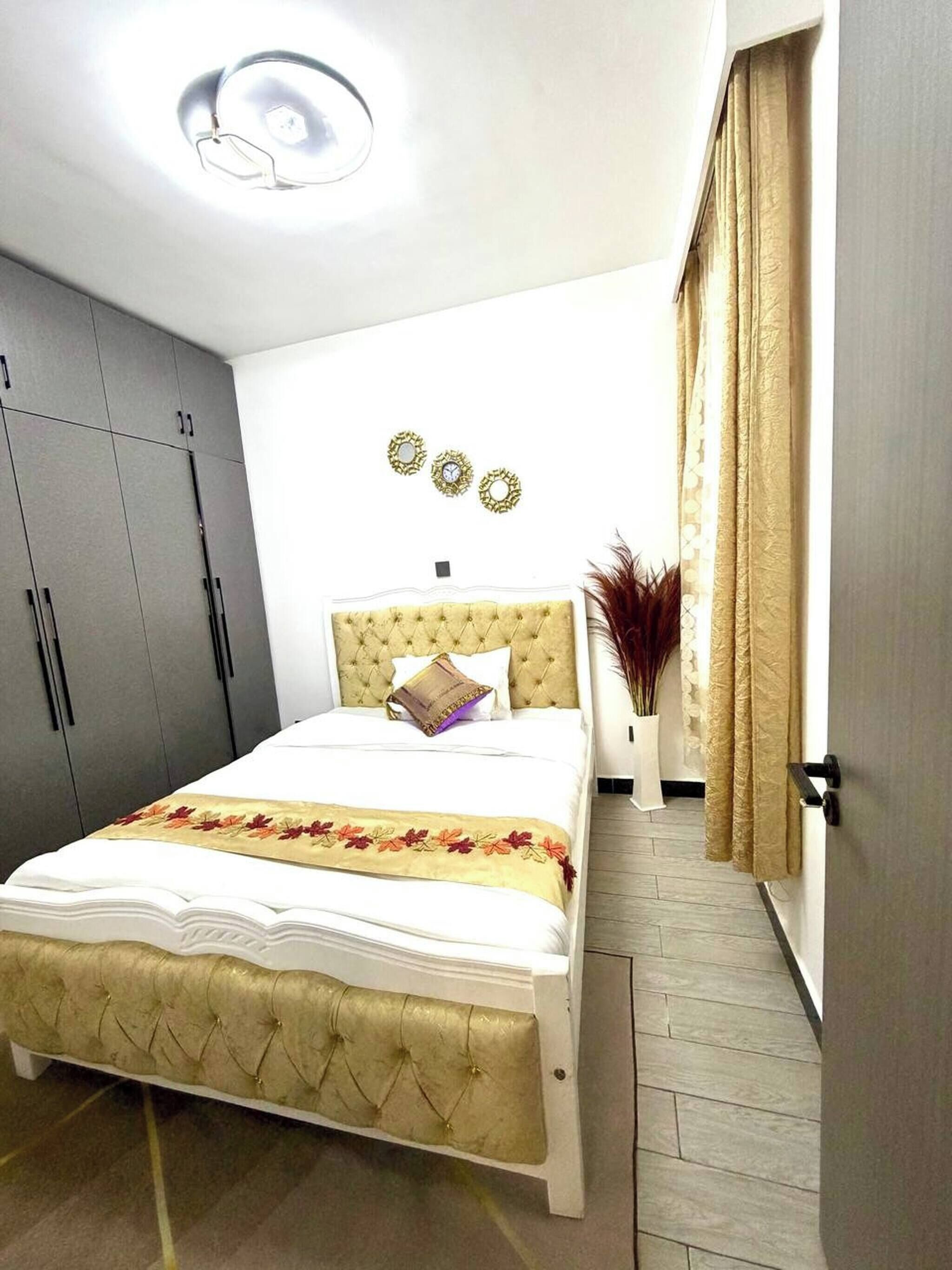 A bedroom with a bed, wardrobe, and decorative wall mirrors.