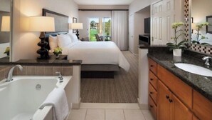 A hotel room with a large bed, a separate bathroom with a bathtub, a sink, and a mirror. - April 12-16th - FLASH SALE - Marriott Shadow Ridge - Full Access Resort (Palm Desert)