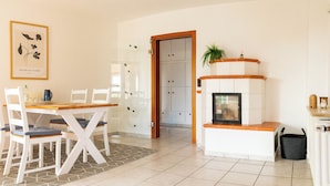 Uma sala de jantar com mesa e cadeiras, lareira e uma porta que dá para outro espaço.