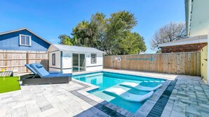 Un patio trasero con piscina, casa de juegos cubierta y valla de madera.