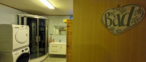 Een wasserette met een wasmachine, droger en een droger in een glazen kast.
