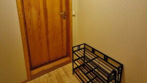 A hallway with a wooden door, a black metal rack with hooks, and a black metal bench. - Studio with fitness room (Troms)