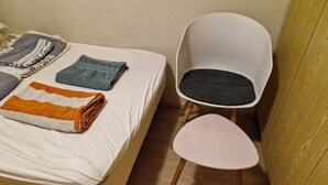 A bed with folded blankets and a chair with a cushion. - Studio with fitness room (Troms)