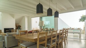 Un comedor amplio con una gran mesa de madera, múltiples sillas y lámparas colgantes.