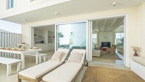 Un espacio habitable moderno con comedor, dos sillones de descanso, una cocina y un televisor al fondo.