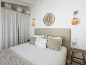 A bedroom with a bed, bedside tables, wall-mounted lamps, and a decorative wall piece.