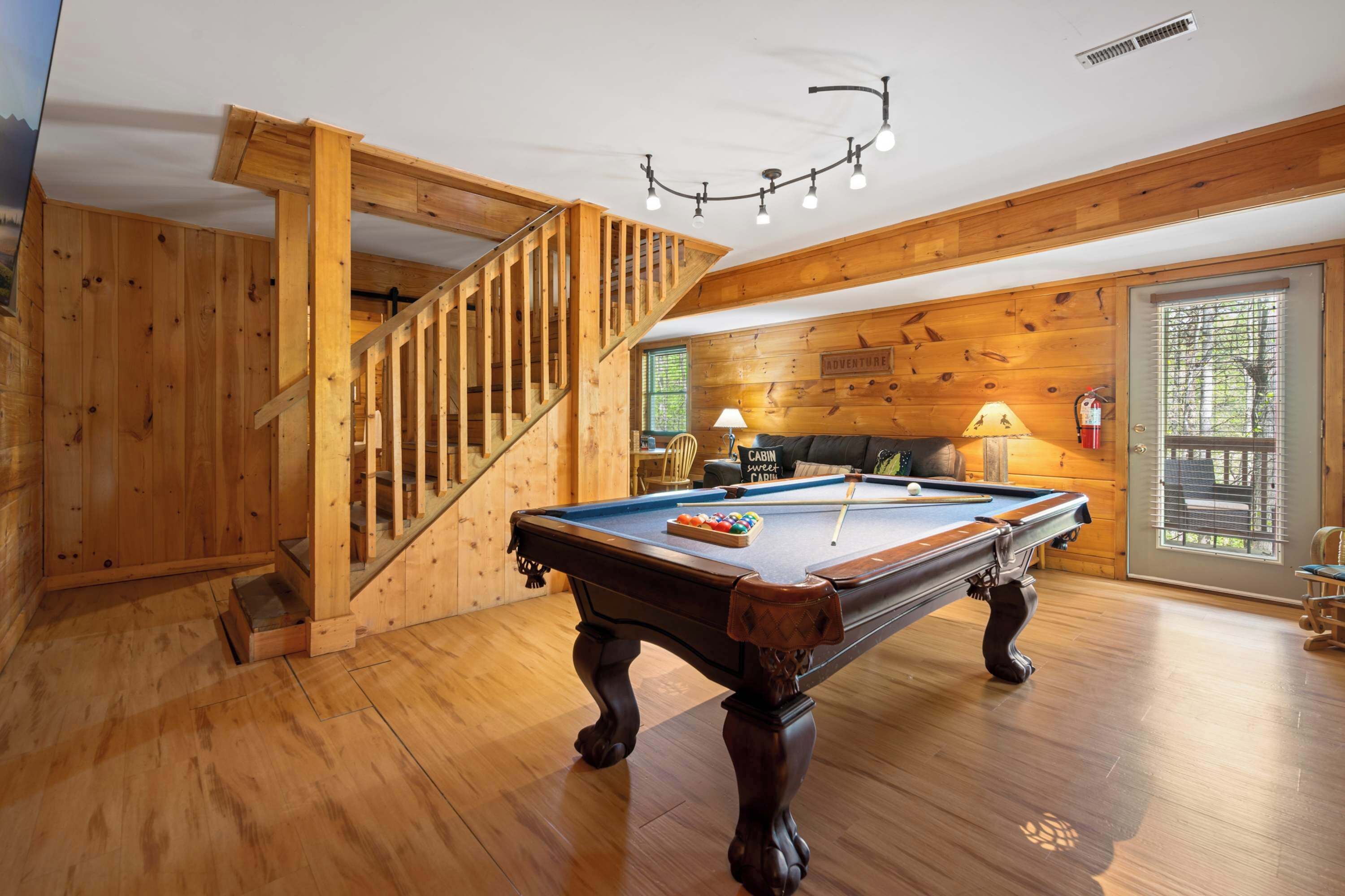 Een houten interieur met een pooltafel, een trap en een bank.