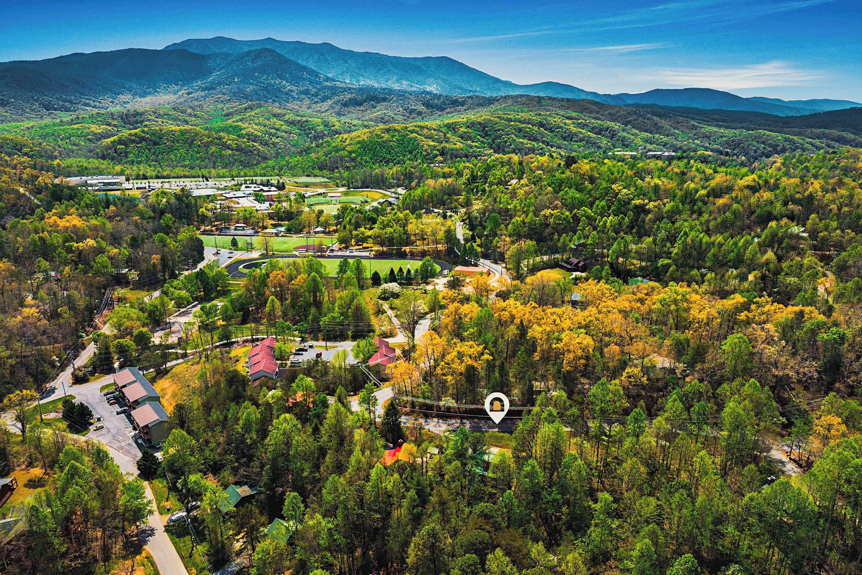 An aerial view of a residential area with houses, roads, and a large green park.