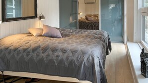 Ein Schlafzimmer mit einem Bett, einem Spiegel, einer Lampe und einer Glastür, die auf einen Balkon führt.
