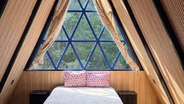 Ein zimmliches Zimmer mit einem Bett, zwei Nachttischen und einem Fenster mit geometrischem Muster.