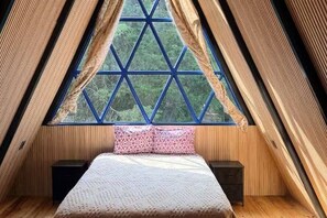 Ein zimmliches Zimmer mit einem Bett, zwei Nachttischen und einem Fenster mit geometrischem Muster.