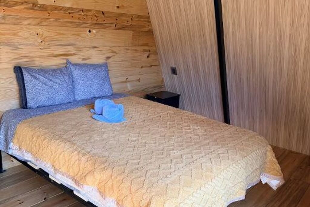 A bed with a quilted cover, two pillows, and a small bedside table.