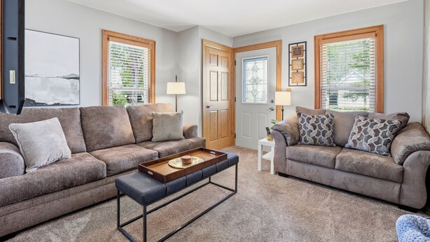 A living room with two sofas, a coffee table, a door with a glass panel, and a framed picture on the wall. - The Appleton Downtown Den (Appleton)