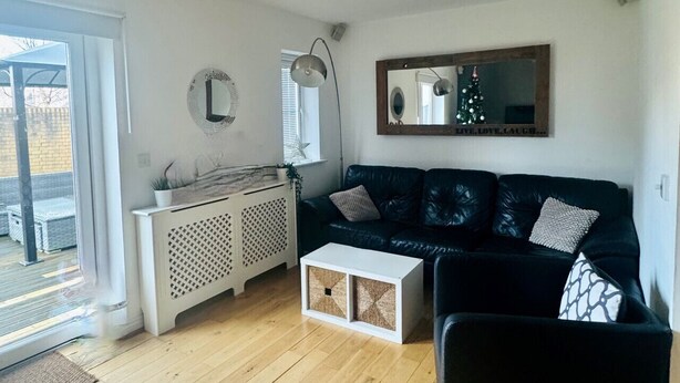 Un salon avec un canapé noir, une table basse blanche et un grand miroir au mur.